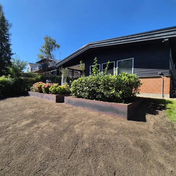Cortenstålkant om bed med beplantning langs hus og afrettet muld
