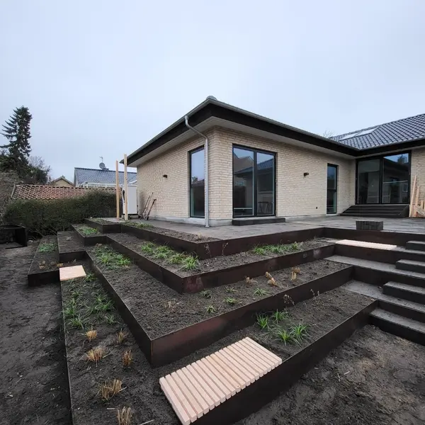 Terrasseret have med støttemure i cortenstål i flere niveauer