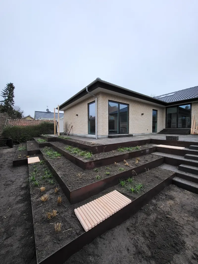Terrasseret have med støttemure i cortenstål i flere niveauer
