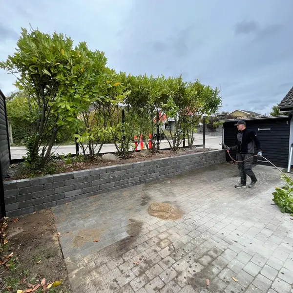 Indkørsel under anlæg med lav støttemur i betonblokke og ny belægning