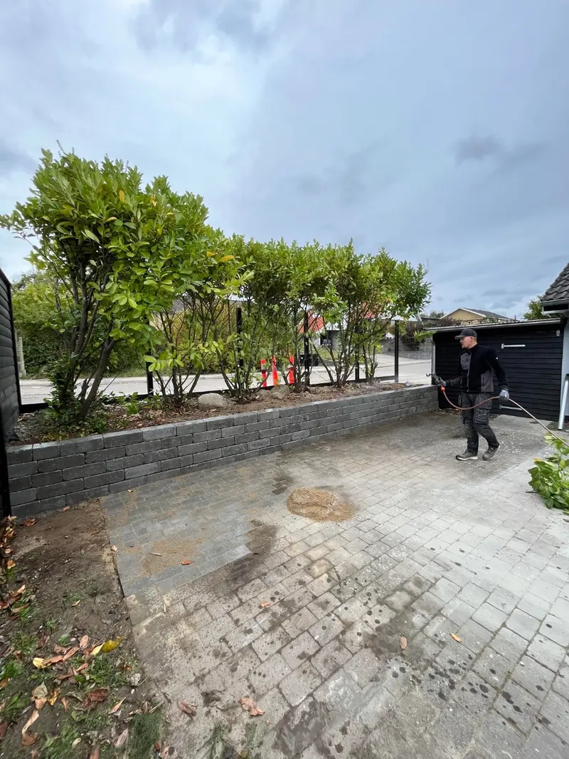 Indkørsel under anlæg med lav støttemur i betonblokke og ny belægning