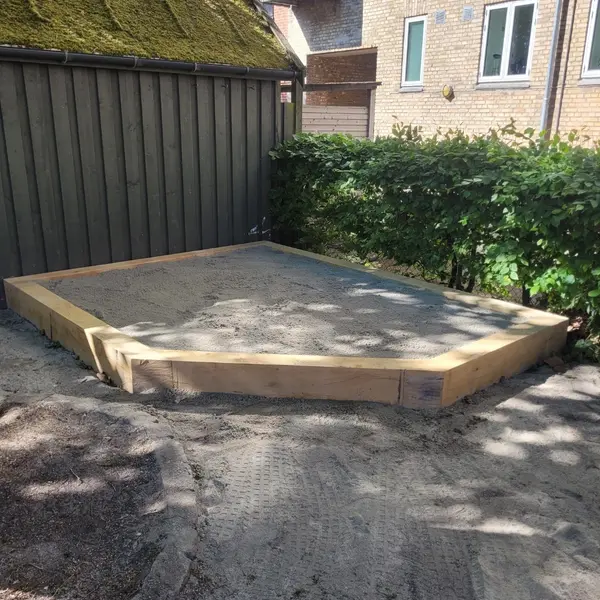Ramme i træ udlagt som underlag på afrettet grus bag hus