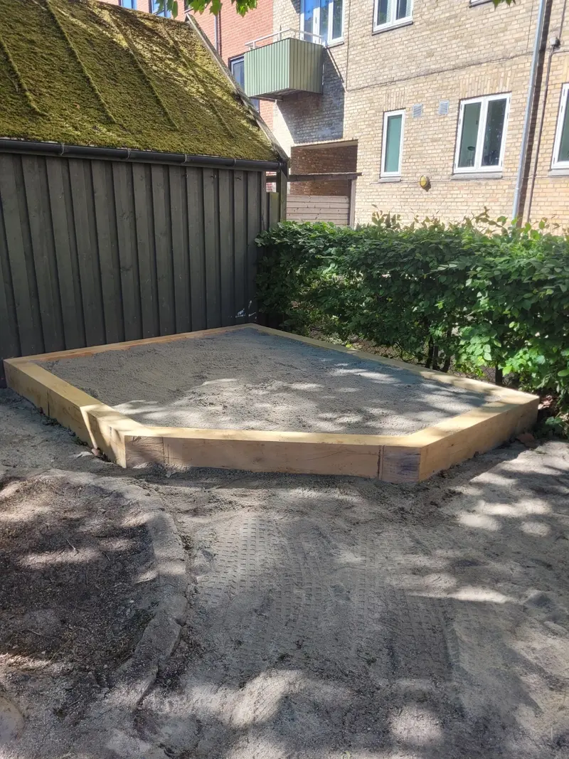Ramme i træ udlagt som underlag på afrettet grus bag hus